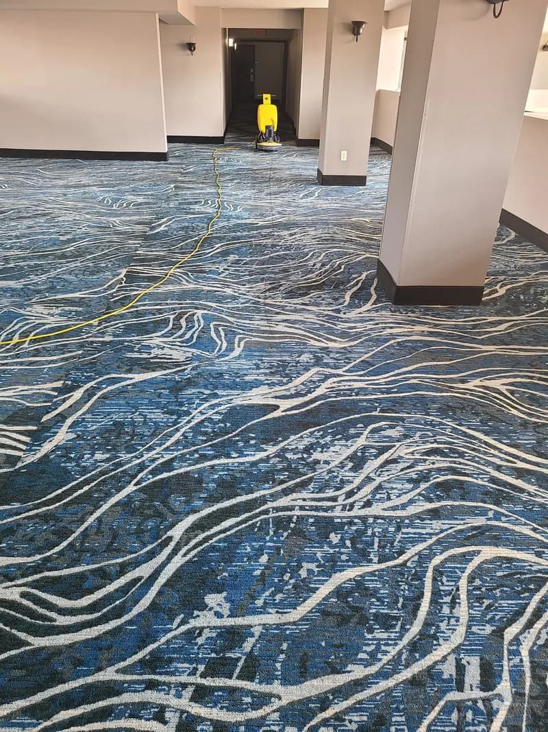 Low-moisture cleaning machine working down a patterned commercial hallway carpet