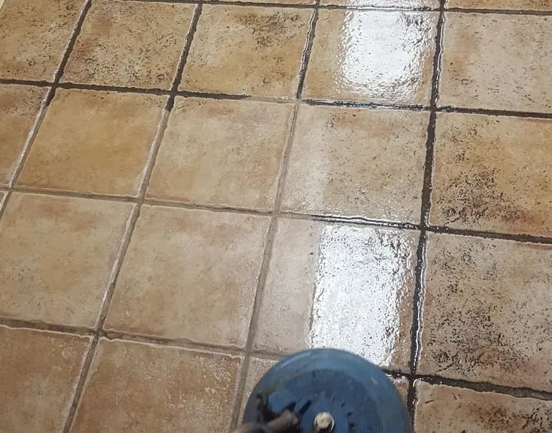 Spinner tool cleaning tan floor tile, with dark grout ahead of it and clean grout behind