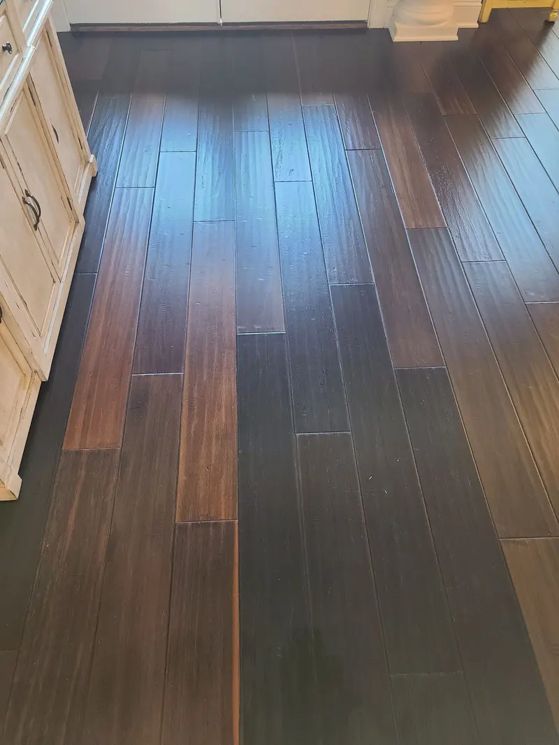After: Dark hardwood floor beside kitchen cabinets after cleaning, with an even sheen