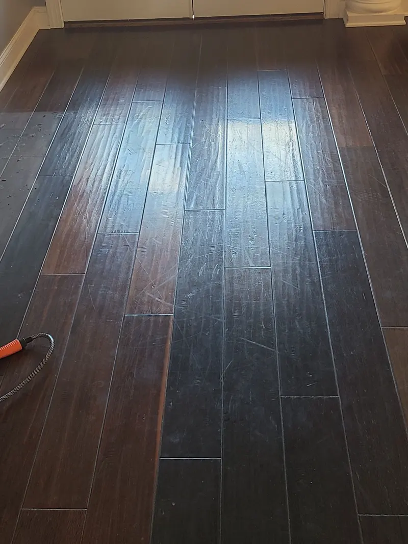 Before: Dark hardwood floor with scuffs and dull traffic wear before cleaning