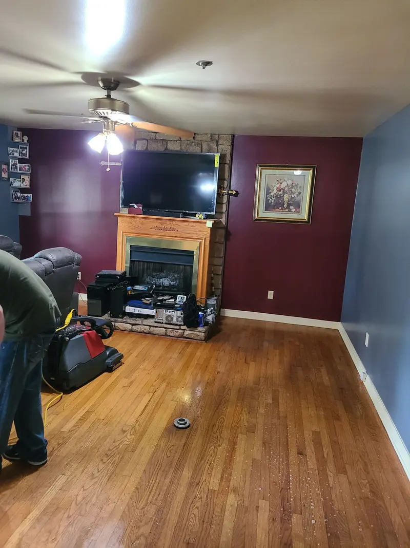 Technician cleaning an oak hardwood floor in a living room