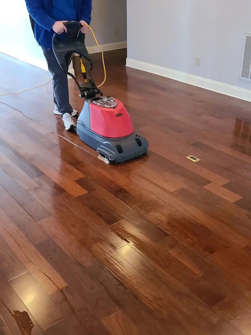Technician running a floor machine across a cherry hardwood floor