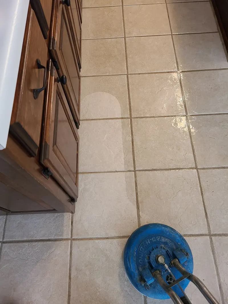 Kitchen tile floor beside wood cabinets being cleaned with a spinner tool
