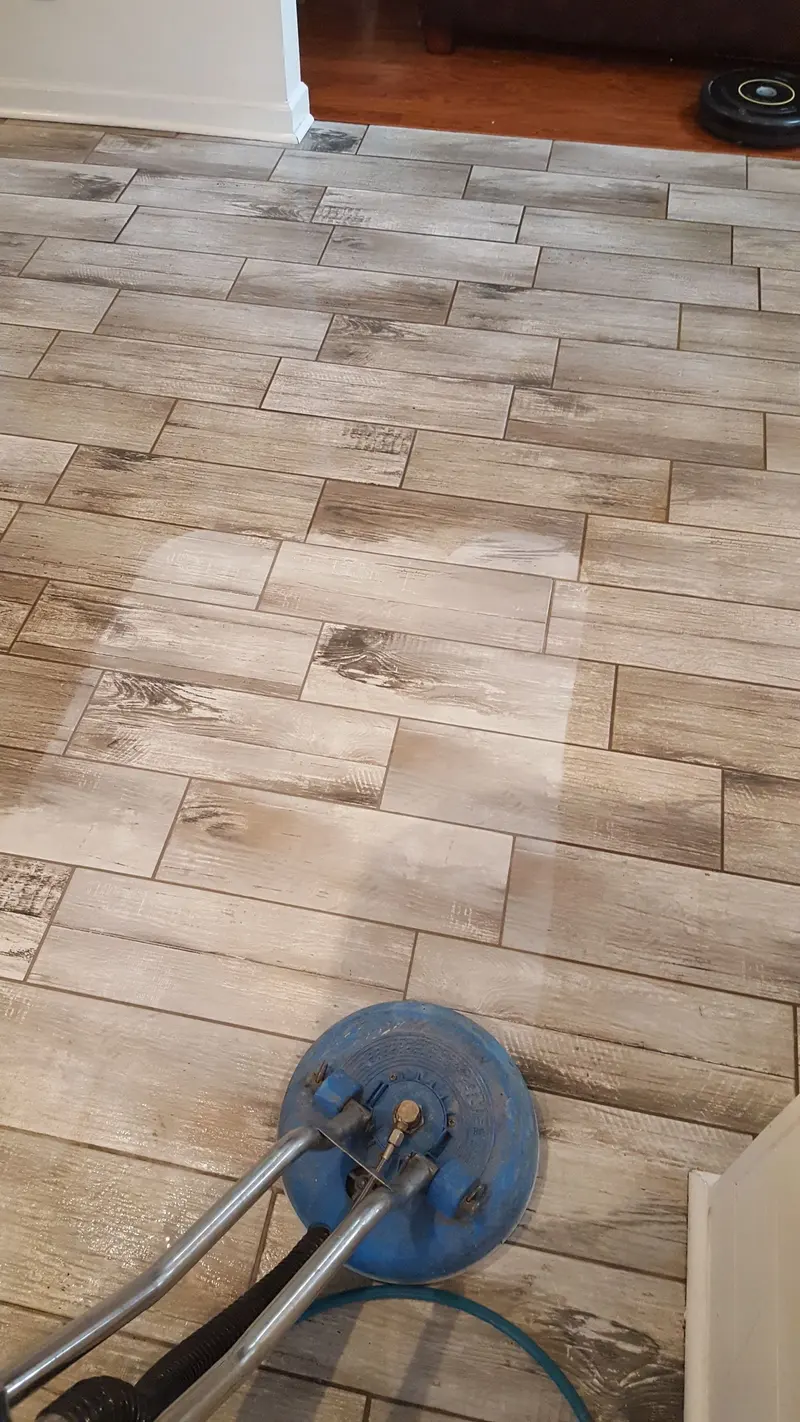 Wood-look plank tile being cleaned with a spinner tool, with the cleaned path visible