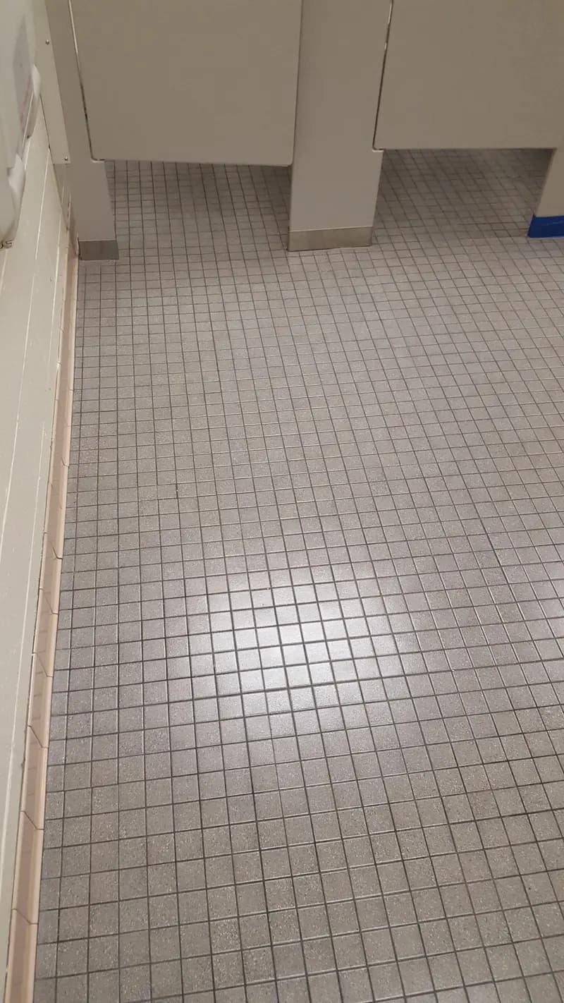 Restroom tile floor beside the stalls after tile and grout cleaning