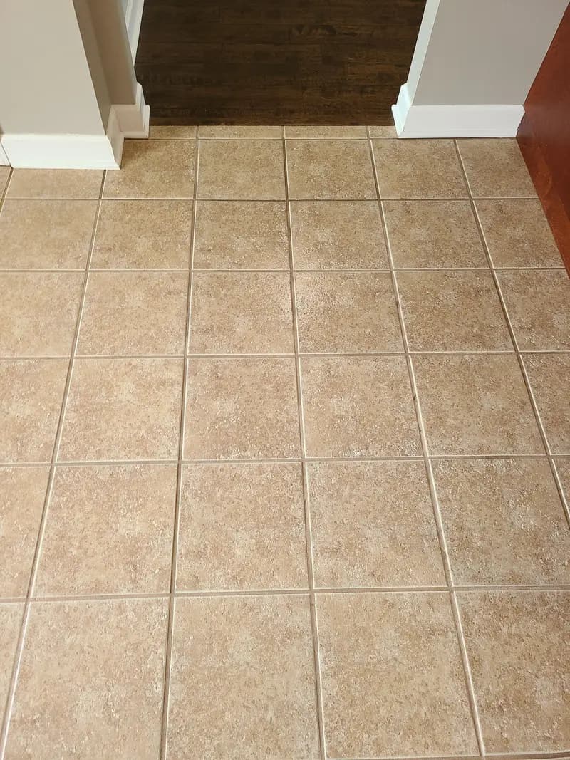 After: Tan tile floor at a doorway with lighter grout lines after cleaning