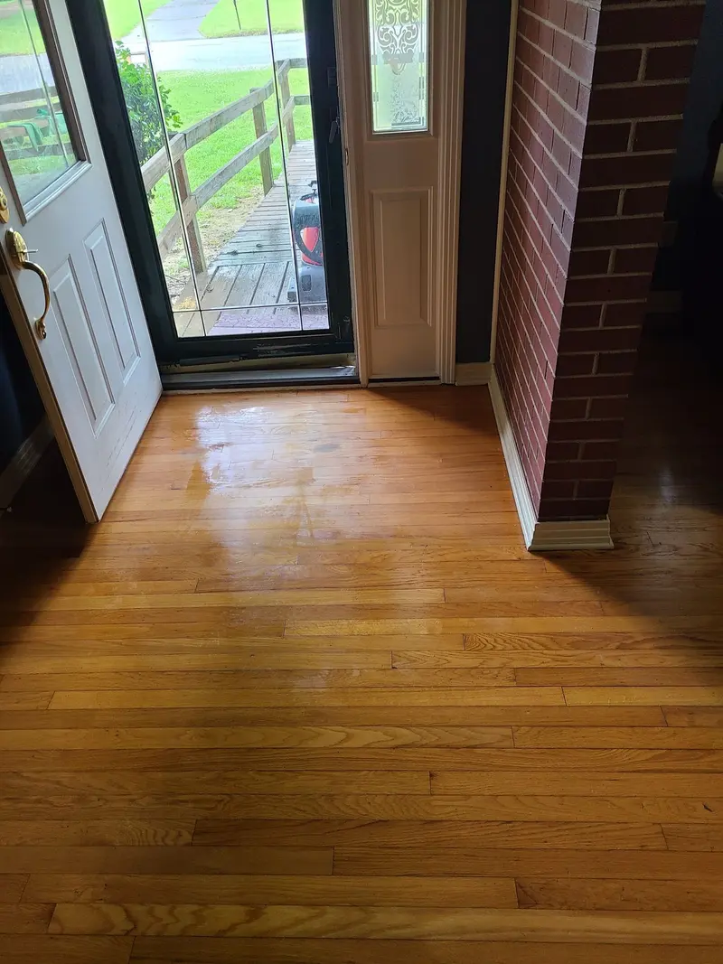 Clean oak hardwood floor in an entryway with the front door open