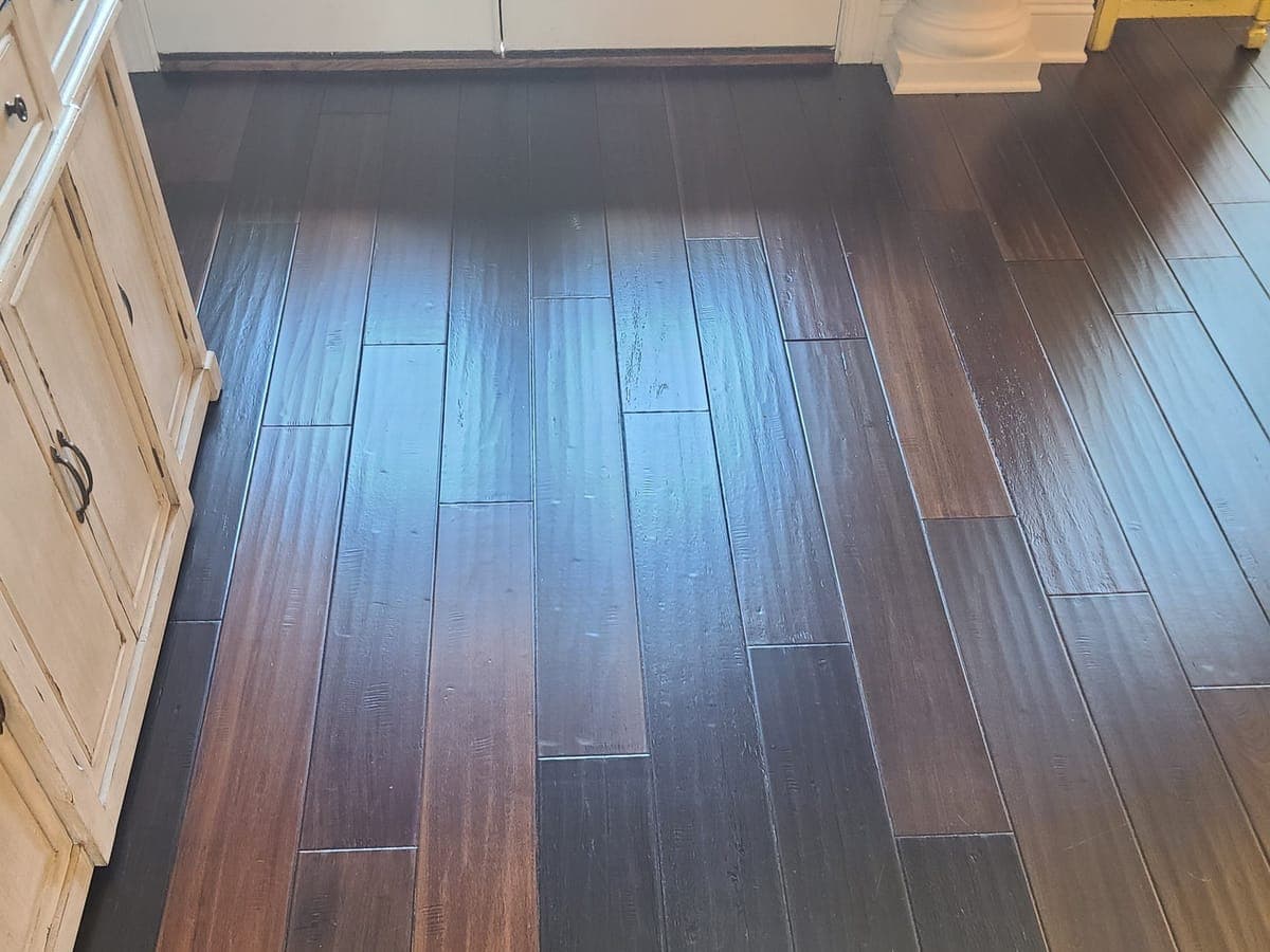 Dark hardwood floor beside kitchen cabinets after cleaning, with an even sheen