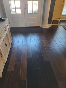 Dark hardwood floor in an entryway beside white cabinets and a front door