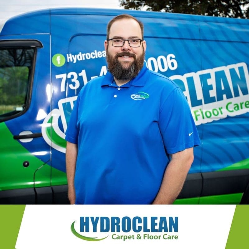 HydroClean team member in a blue company shirt standing in front of the company van
