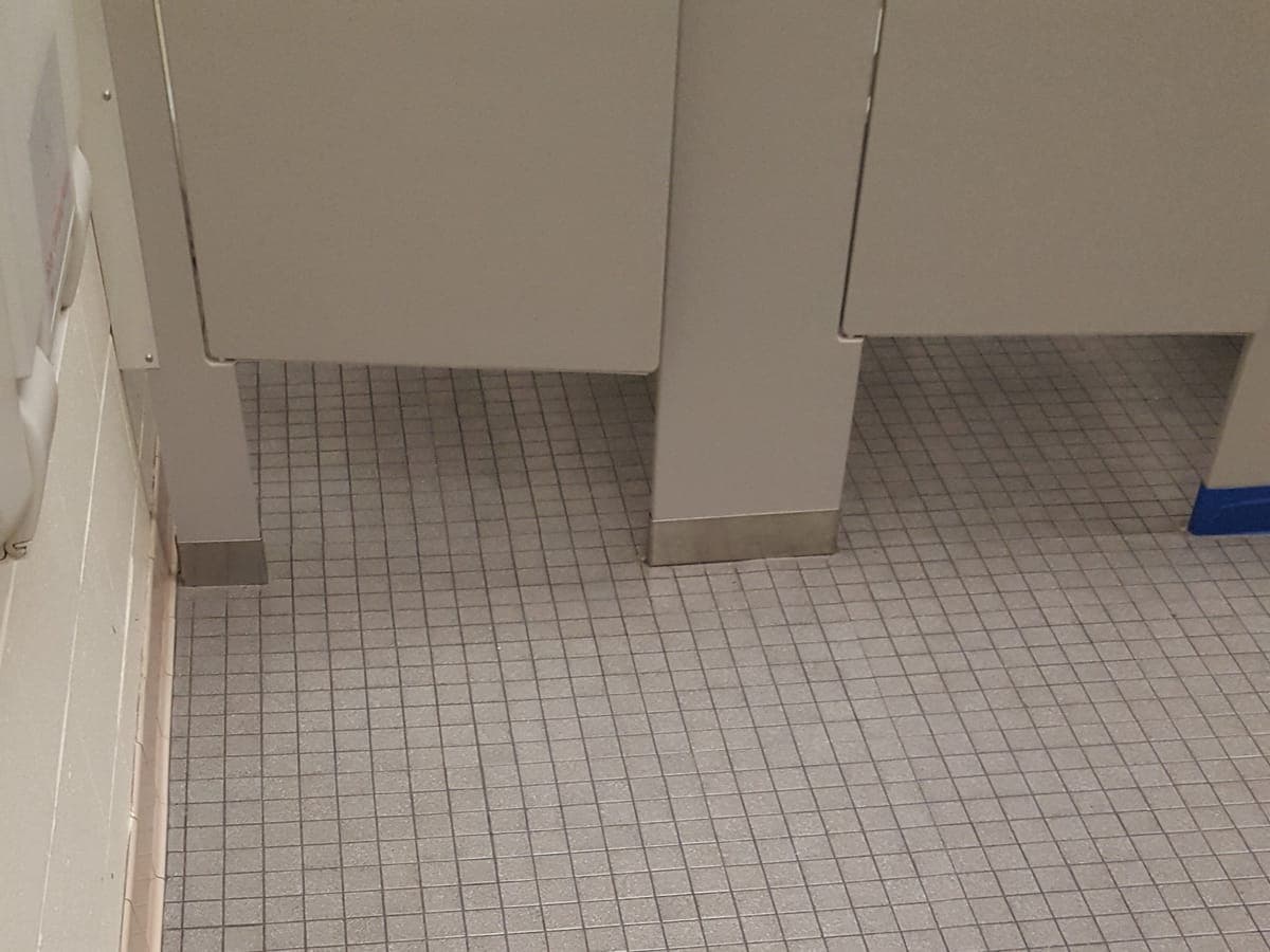 Restroom tile floor beside the stalls after tile and grout cleaning