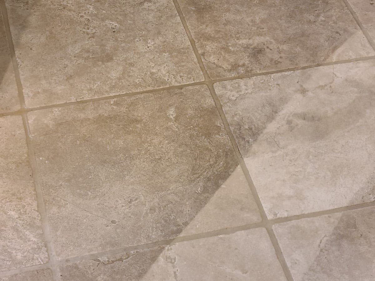 Stone-look tile floor with a diagonal line between the cleaned and uncleaned sections