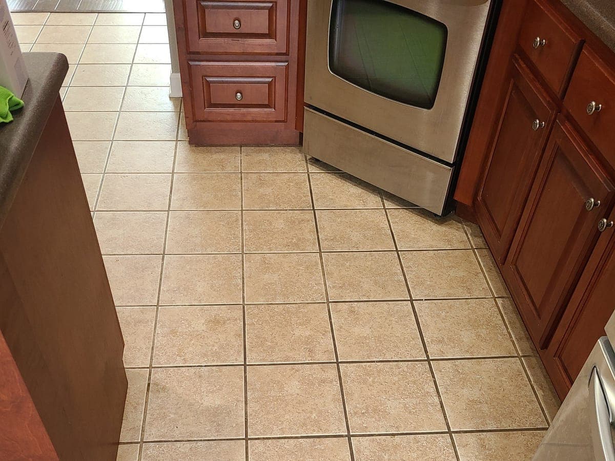 Kitchen tile floor with dark grout lines before cleaning